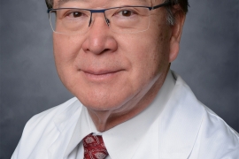 Photo of David Pao in a white lab jacket and red tie.